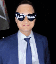 a man in a suit and tie is wearing heart shaped sunglasses with the word love on them