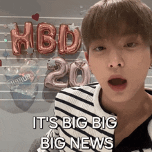 a young man says it 's big big big news while standing in front of balloons