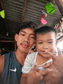 a man wearing a nike shirt holds a child