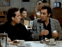 two men are sitting at a table with plates of food .