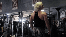 a man in a black tank top stands in front of a machine that says der