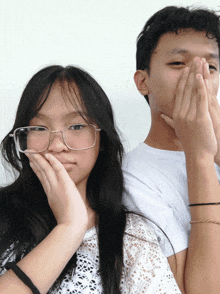 a boy and a girl are posing for a picture and the girl is wearing glasses