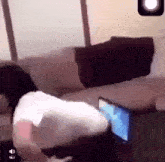 a person is laying on a couch with their head on a laptop .