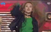 a woman in a green shirt is dancing on a stage in front of a sbs sign