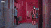 a man is standing in a hallway holding a gun in his hand .