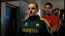 a man wearing a green pakistan jersey stands in a hallway