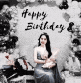 a woman sitting in front of a happy birthday sign