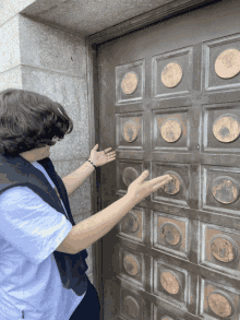 a man reaches out to open a door with gold circles