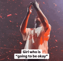 a man in a white shirt with the word drake on it holds his hands in the air