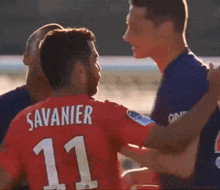 a soccer player wearing a fly emirates jersey talks to another player