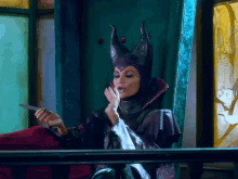 a woman dressed as maleficent holds a knife in her hand