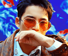 a man wearing a heart shaped sunglasses covering his mouth with his hand