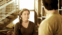 a man and a woman are looking at each other in a room with stairs in the background