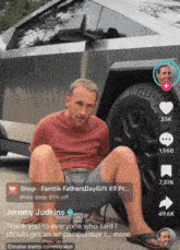 jeremy judkins is sitting on the ground in front of a car with his feet up