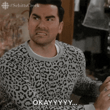 a man in a leopard print sweater says " okay "