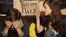 a man and a woman are sitting in front of a pillow that says welcome to our class web