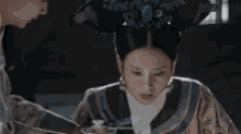 a woman in a traditional costume is sitting next to a man in a dark room .