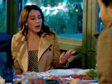 a woman in a trench coat sits at a table