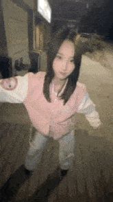 a young woman in a pink jacket is standing on a wooden floor .