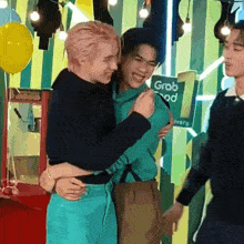 a group of young men hugging each other in front of a sign that says grab food