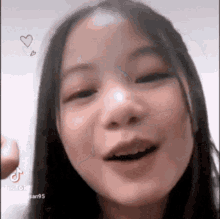 a close up of a young girl making a funny face with a heart above her head .