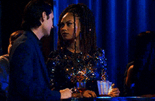 a man and a woman are sitting at a table in a bar .