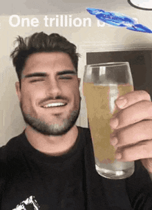 a man with a beard is holding a glass of beer in his hand .
