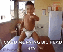 a baby in a diaper is standing on a bed with the words `` good morning big head hey '' .