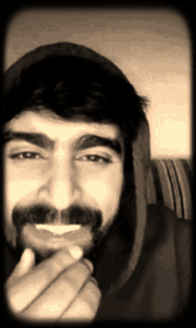 a man with a beard wearing a black hoodie is smiling