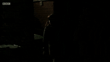 a woman walking down a dark alleyway with bbc written on the bottom right