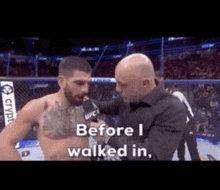 a man is talking to another man in a boxing ring while a referee looks on .