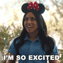 a woman wearing minnie mouse ears has the words i 'm so excited above her