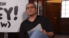 a man sitting in front of a sign that says " ew "