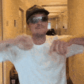 a man wearing sunglasses and a baseball cap is pointing at the camera