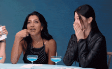 two women are sitting at a table with a drink in a glass that says juicy