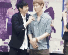 two men are standing next to each other and one is holding a microphone in his hand .