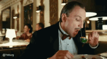 a man in a tuxedo is eating with a spoon and fork