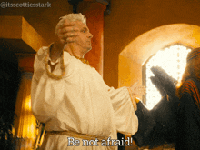 a man in a white robe says be not afraid in front of a window