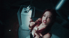 a woman with red hair is standing in front of a glass box with a shoe on it