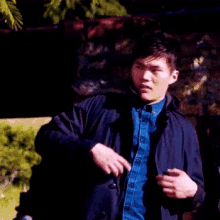 a man wearing a blue shirt and a black jacket is standing in a dark room .