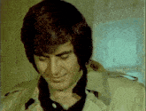 a man in a trench coat is looking down at something