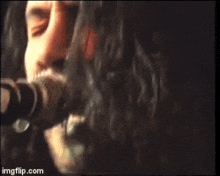 a man is singing into a microphone while playing a guitar in front of a sign that says ha
