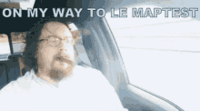 a man smoking a cigar in a car with on my way to le maptest written above him