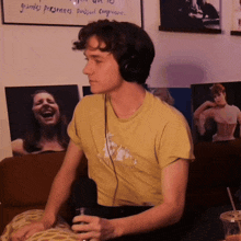 a man wearing headphones is sitting on a couch in front of a sign that says " grandes persones "