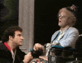 a man is kneeling down next to a woman in a wheelchair .