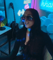 a woman wearing sunglasses stands in front of a wall that says hustle