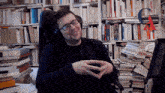 a man wearing headphones sits in front of a stack of books one of which is titled " l' autre "