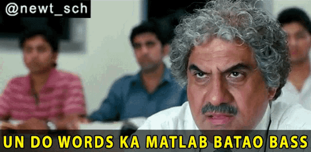 a man with gray hair and a mustache is sitting in a classroom with a caption that reads un do words