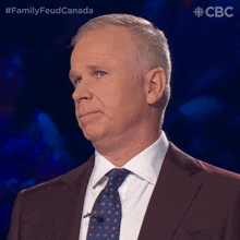 a man in a suit and tie is standing in front of a blue background with the letters cbc on it
