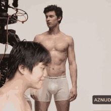 a shirtless man in calvin klein underwear stands next to a shirtless boy